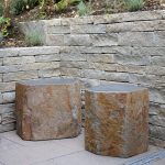 Gartensitzplatz mit Basaltsteinen vor einer Trockenmauer aus Natursteinen